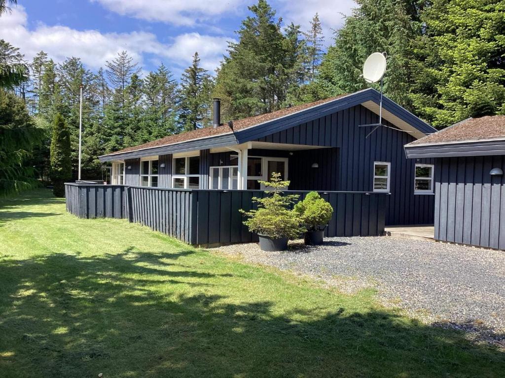 a blue house with a fence next to a yard at 8 person holiday home in Blokhus-By Traum in Blokhus