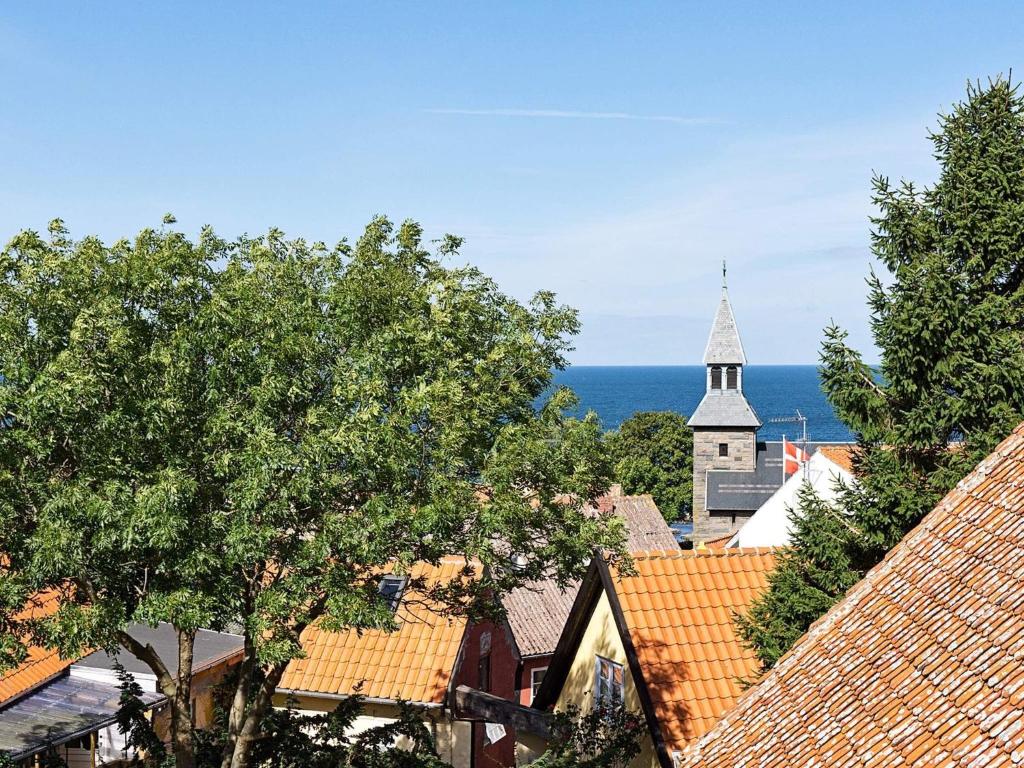a view of a town with a church and the ocean at 4 person holiday home in Gudhjem-By Traum in Gudhjem