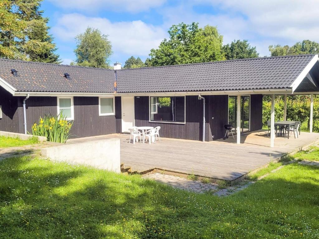 a house with a wooden deck in the yard at 8 person holiday home in Melby in Melby