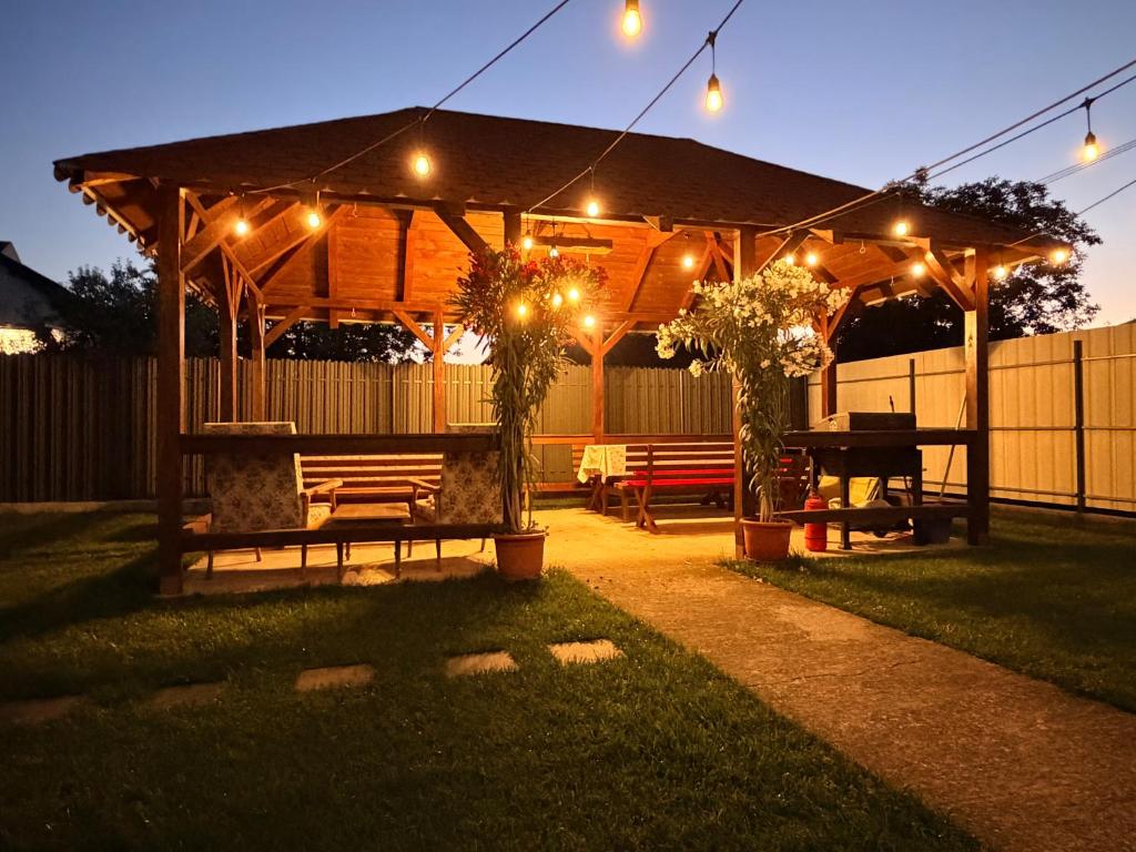 a wooden gazebo with a picnic table and lights at Casa Alba - Tasnad in Tăşnad