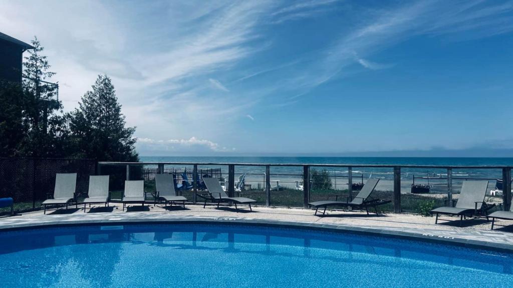 a swimming pool with chairs and a view of the ocean at Wasaga Daze - Unit B in Wasaga Beach