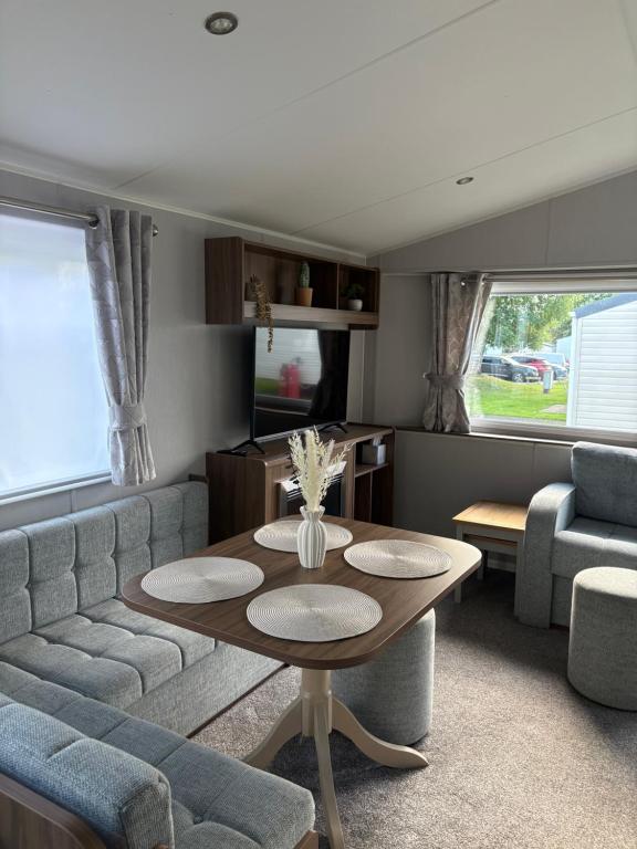 a living room with a table and a couch at Sea Breeze Lodge in Longniddry