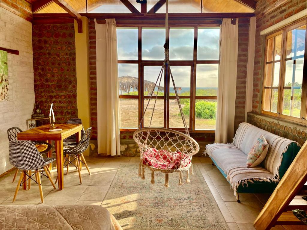 a living room with a couch and a table and windows at Nativo Lodge in Playas