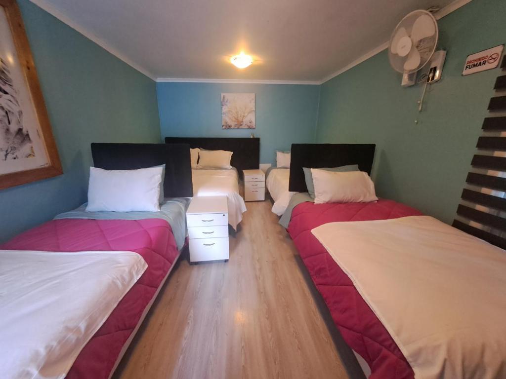 three beds in a room with wooden floors at HOSTAL EL ARoMO CHILLÁN in Chillán