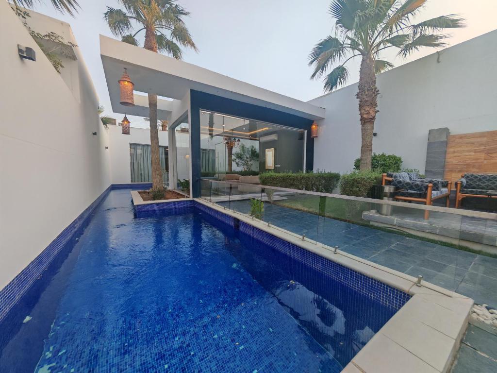 a swimming pool in front of a house at Al Salateen Villas Resort in Al ‘Ammārīyah