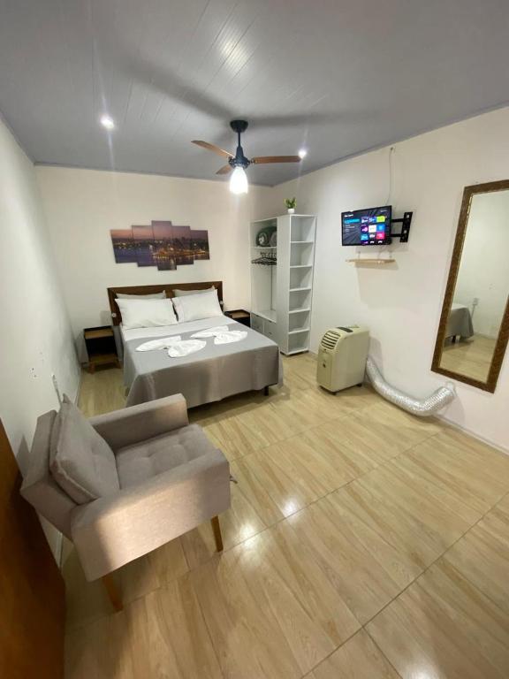 a bedroom with a bed and a couch and a television at kitnet Residencial Ozzy com Garagem Coberta em Betim in Betim