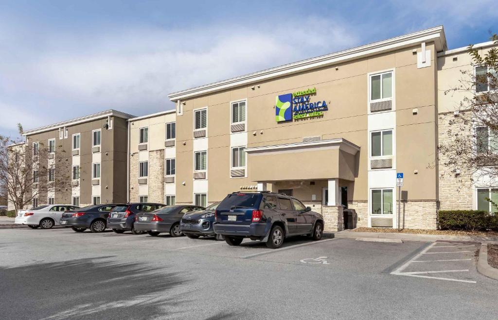 a large building with cars parked in a parking lot at Extended Stay America Select Suites - Orlando - Airport in Orlando