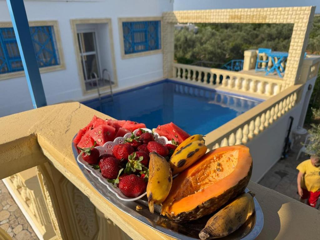 a plate of fruit on a table next to a pool at le petit paradis in Chaba Remada