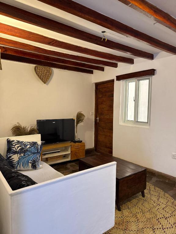 a living room with a white couch and a tv at Mida creek front one bedroom in Watamu