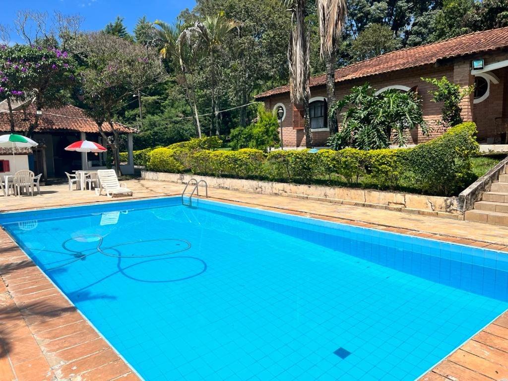 a large blue swimming pool in front of a house at Recanto Rosa Maria in Monte Sião
