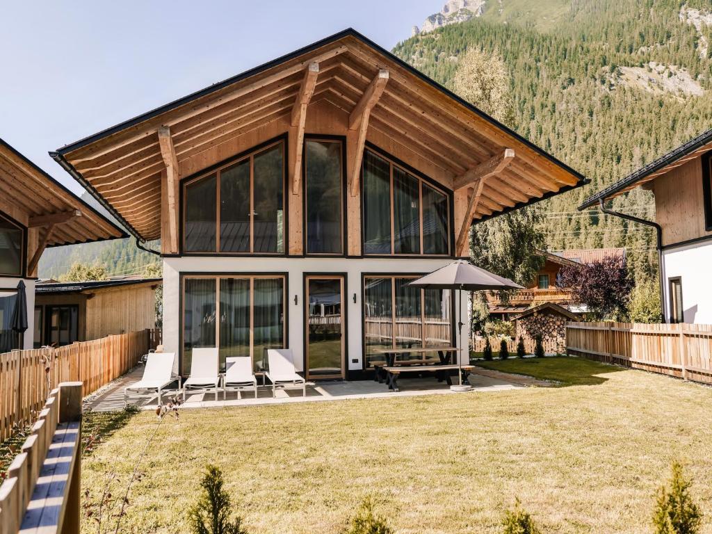 a house with chairs and an umbrella at Your bright chalet with sauna in Bichlbach in Bichlbach