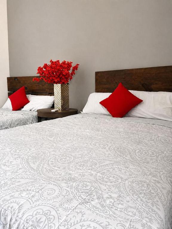 a bedroom with two beds and a vase with red pillows at Hotel Puerta de Jade in Ciudad Valles