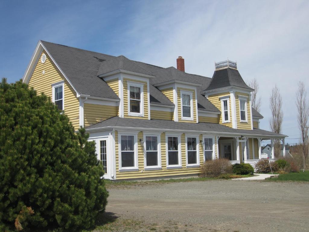 a large yellow house with a gray roof at Auberge Vue d'la Dune - Dune View Inn in Bouctouche