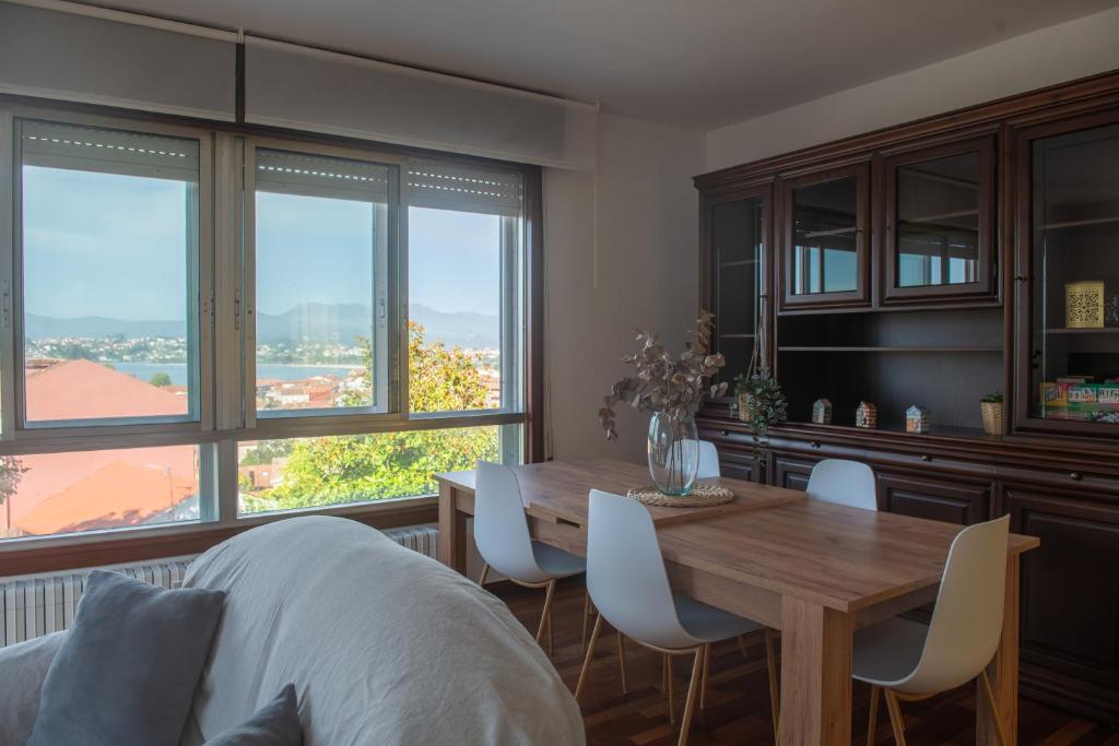 a dining room with a table and chairs and windows at Laxes do Mar in Baiona