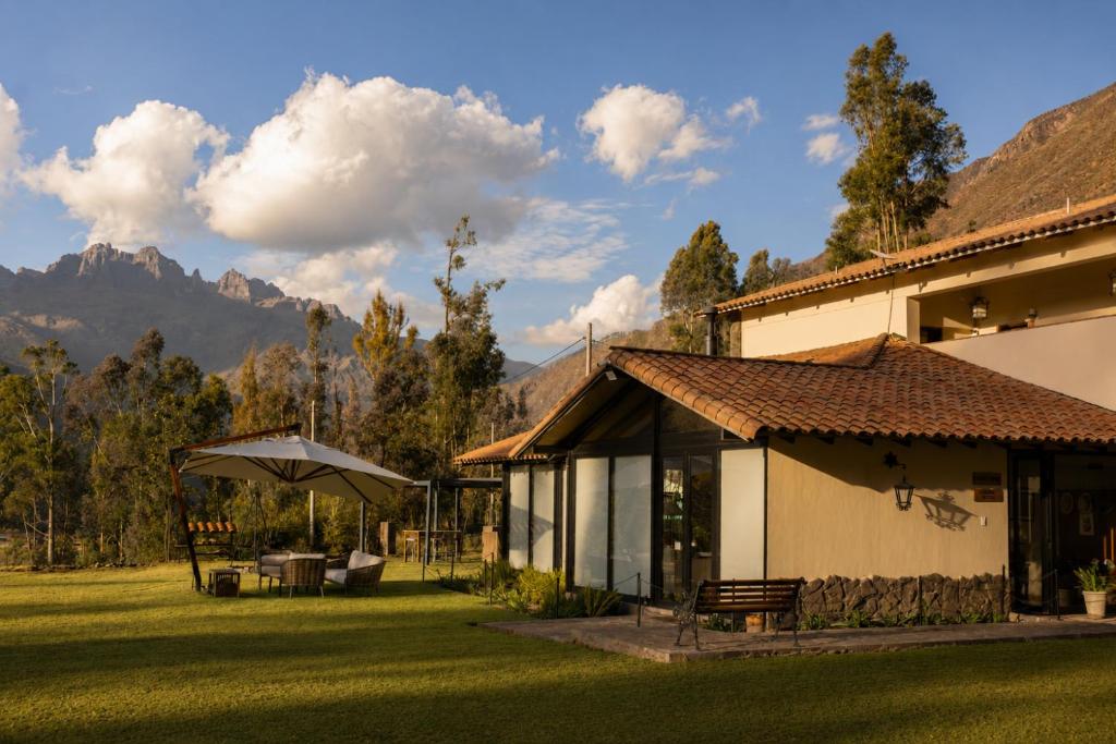 a building with an umbrella next to a grass yard at Sierra Sacred Valley in Urubamba