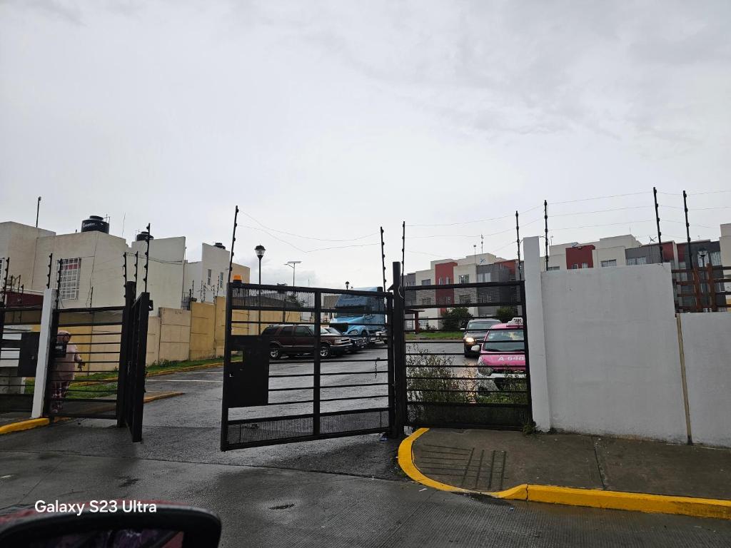 a gate in a parking lot with parked cars at La comodidad a tu alcance in Bata