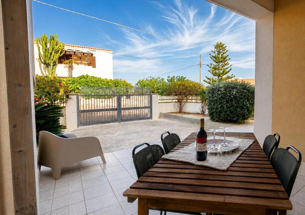 a wooden table with a bottle of wine on a patio at Mediterranea Modica - Seaside Home in Marina di Modica