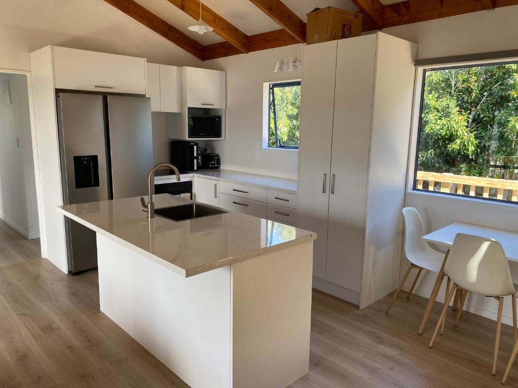 a kitchen with white cabinets and a large window at Mangōnui Harbour Haven in Mangonui