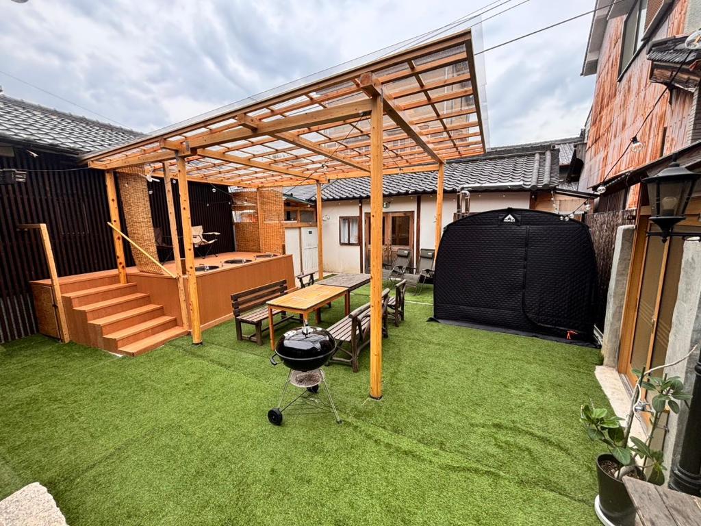 eine Terrasse mit Grill und Holzpergola in der Unterkunft Kominka Wagaya in Higashiōsaka
