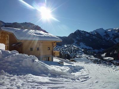 a snow covered building with the sun shining behind it at Chalet L'étagne in Châtel