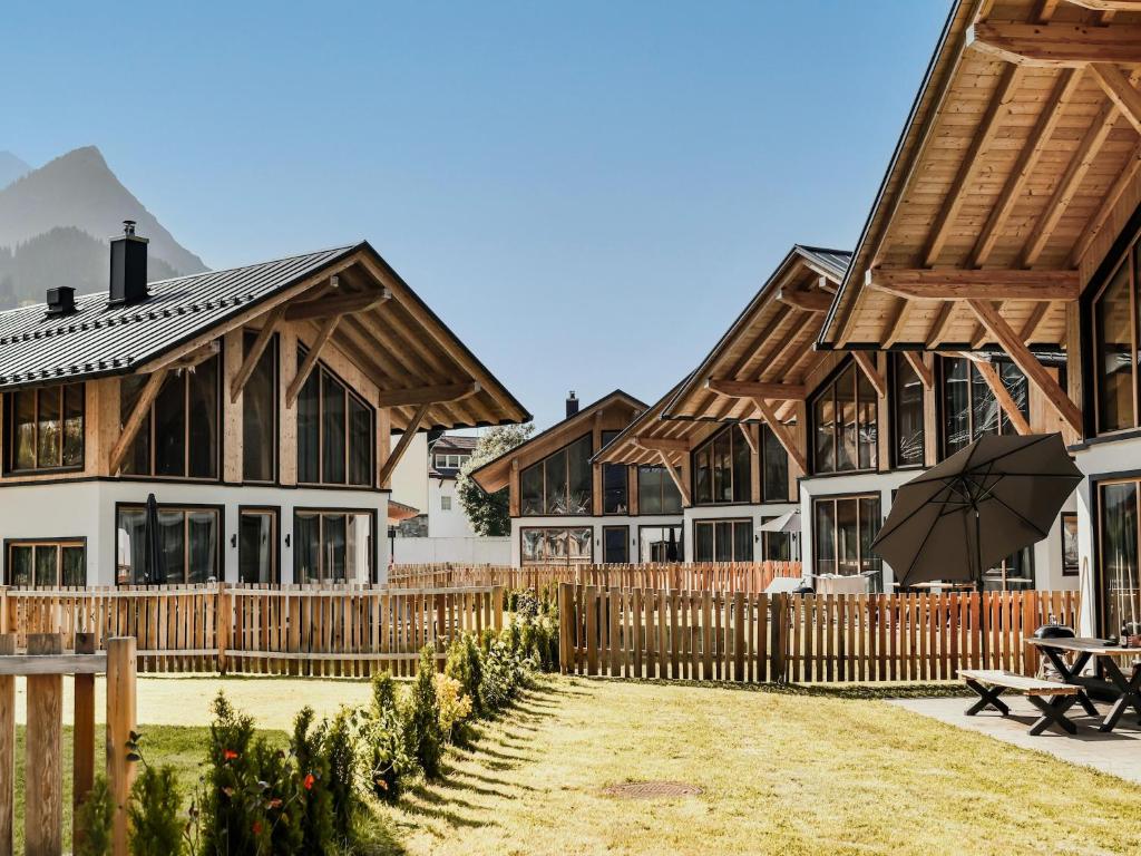 a row of houses with a fence and an umbrella at Modern chalet with sauna, Dein Bichlbach in Bichlbach