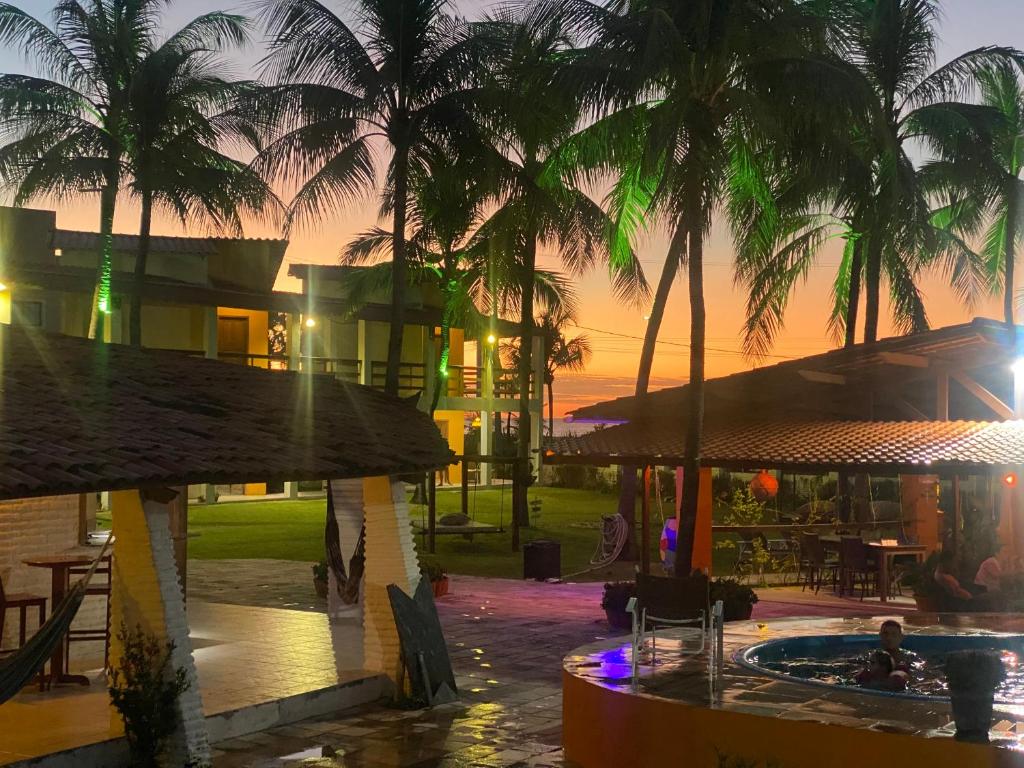 a resort with a pool and palm trees at sunset at Pousada Água Azul in Flecheiras