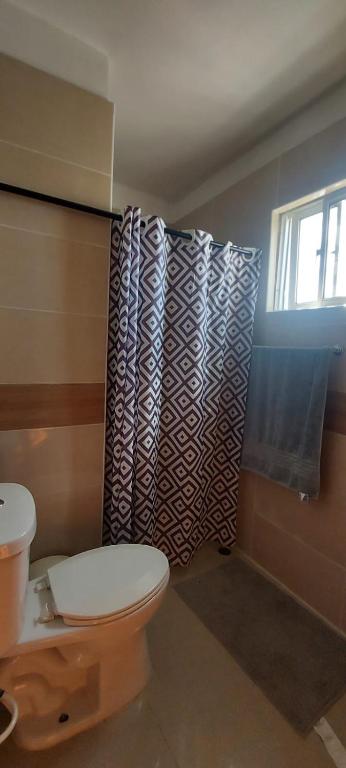 a bathroom with a toilet and a shower curtain at La cubana in Santo Domingo