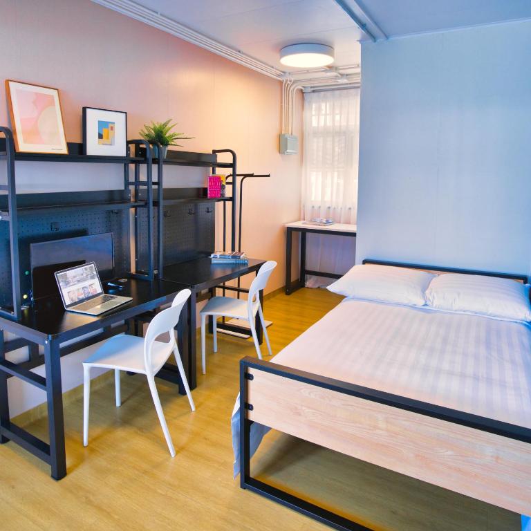 a bedroom with a bed and a desk and a bed and a table at Runway 1331 -ENLIGHT Youth Hostel in Hong Kong