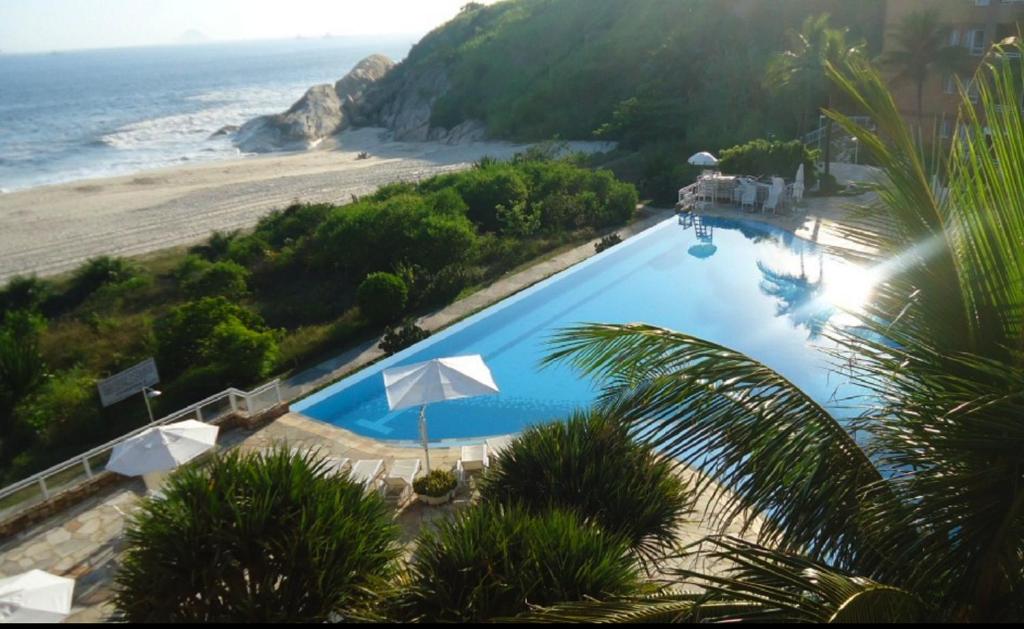 a large blue swimming pool next to a beach at Camboinhas Oceanside Oceanfront in Rio de Janeiro
