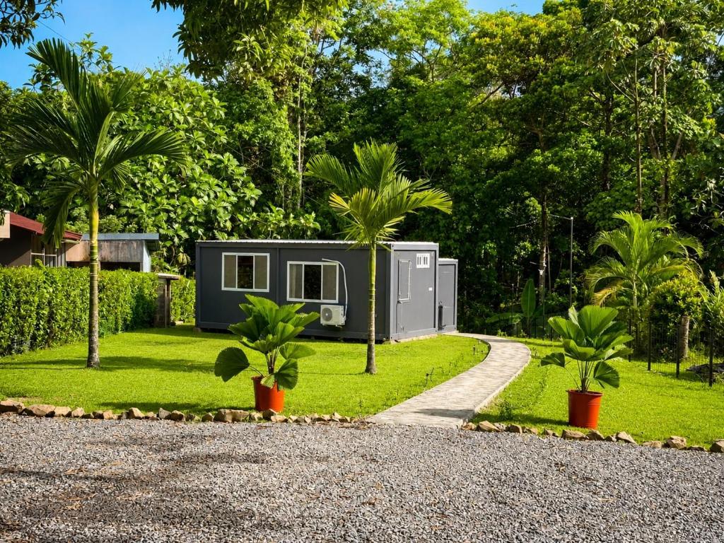 a tiny house in a garden with palm trees at Río Celeste Stay in Rio Celeste
