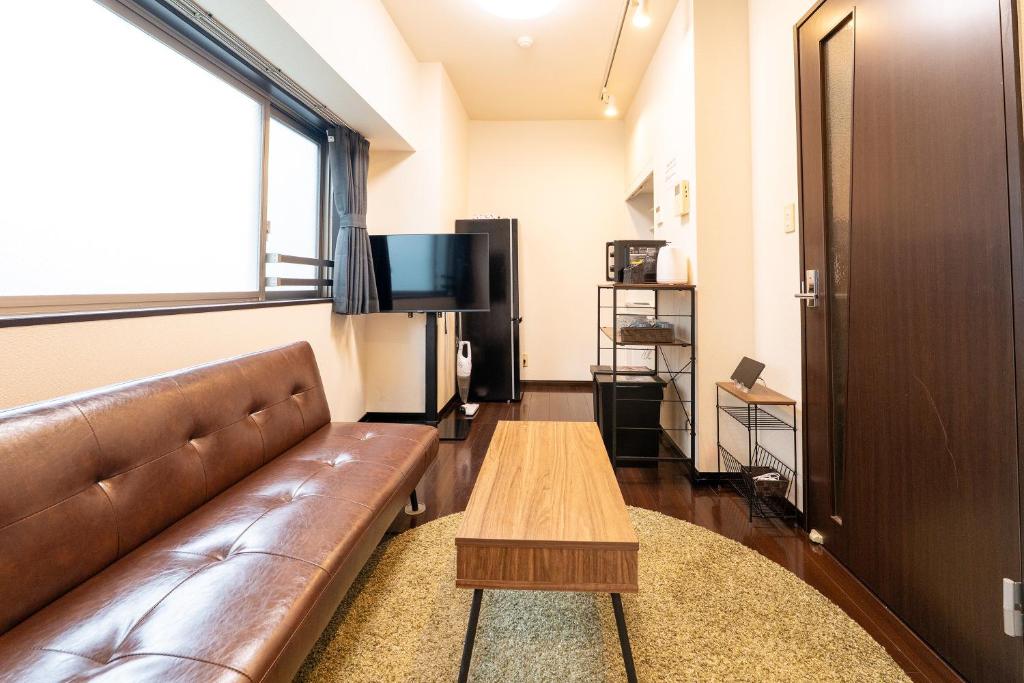 a living room with a brown leather couch and a table at Ruis Hakata in Fukuoka