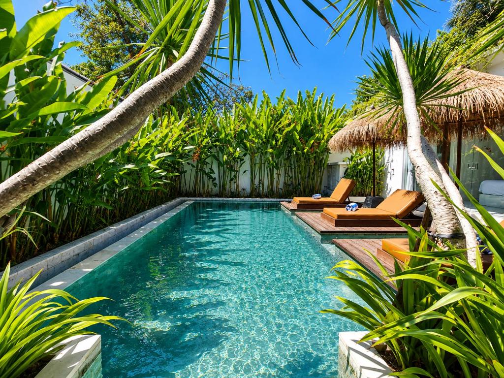 an infinity pool with two chairs and palm trees at Villa Mei 2BR Pool, 200m from Seseh Beach in Dalung