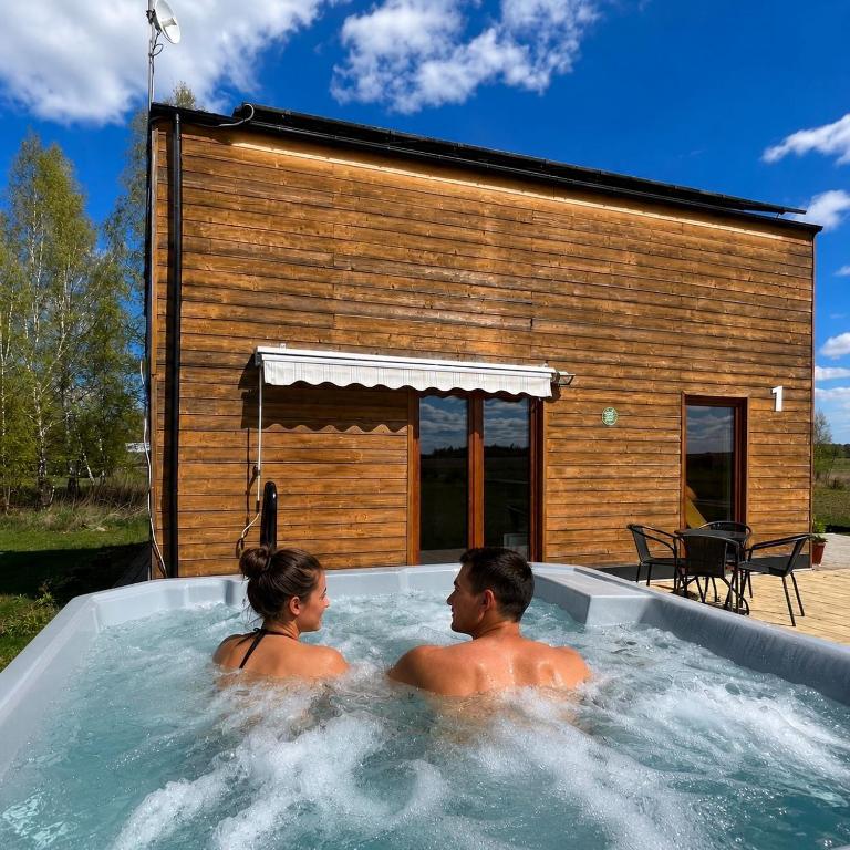 a man and woman sitting in a hot tub at Domek na Roztoczu Sauna & Jacuzzi in Horyniec