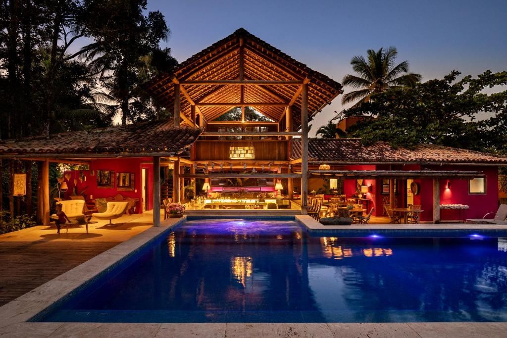 a house with a swimming pool in front of a house at Pousada Hibisco in Trancoso