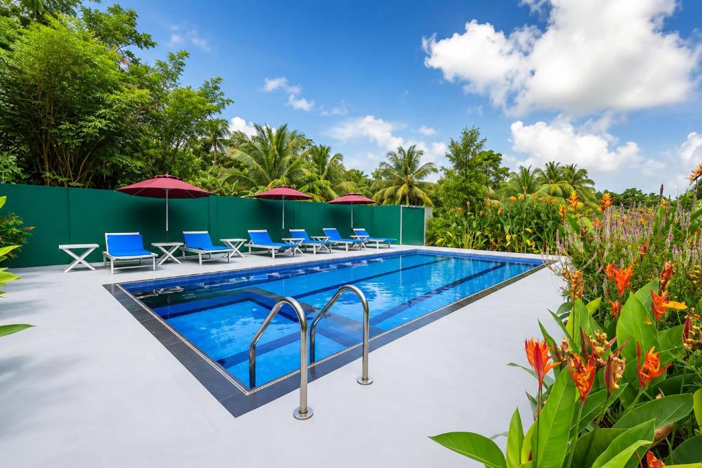 a swimming pool with chairs and umbrellas in a garden at Lion See Hotel - Sigiriya in Sigiriya