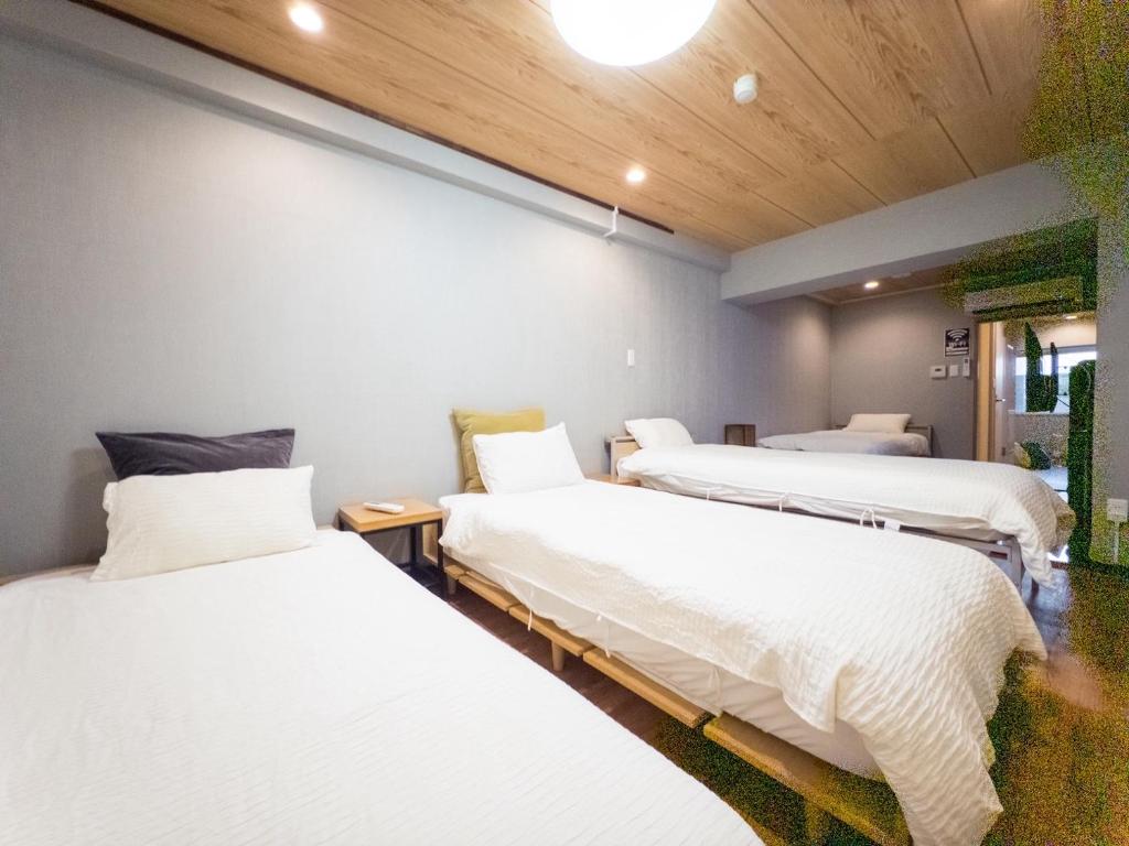 two beds in a room with white sheets at KANDA HOUSE!! Shin-Okubo Walkable Modern Stay with Shinjuku Access in Tokyo