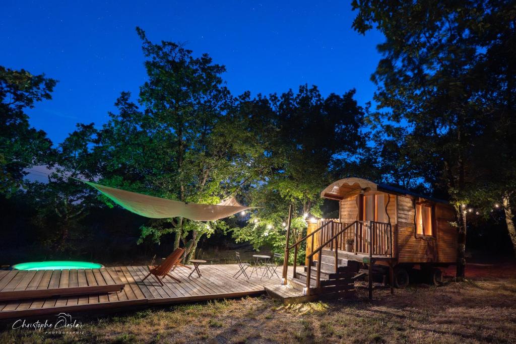 a cabin with a hammock on a deck at night at Roulotte de Combeplane in Carnac-Rouffiac
