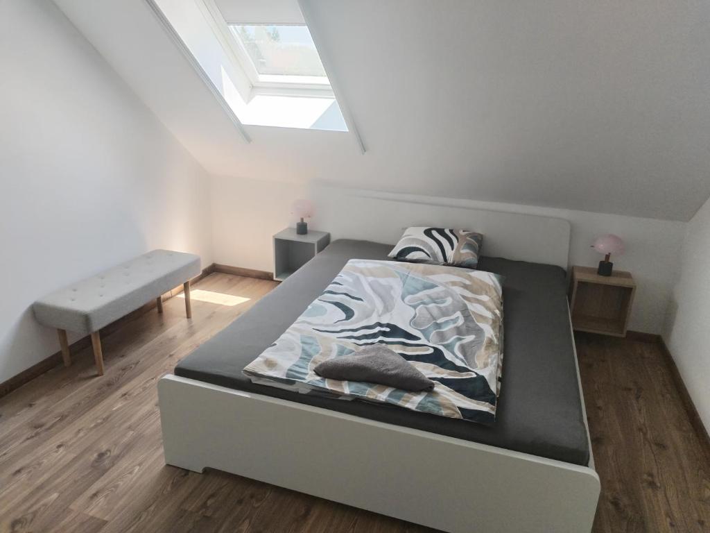 a white bedroom with a bed and a skylight at Dömper Döme Apartman in Balatonlelle