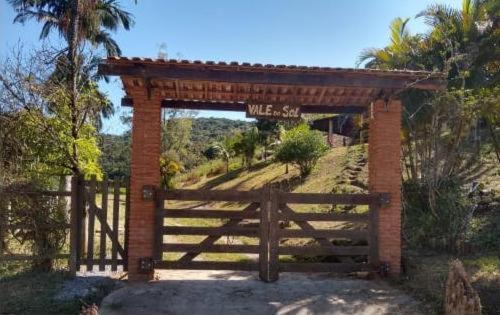 a brick gate with a wooden fence next to a field at Miracatu! Refúgio e Paz nas Montanhas in Miracatu