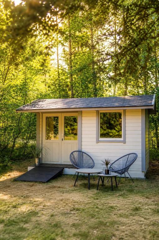 a tiny house with a picnic table and two chairs at A Tiny House Near The Beach in Pērkone