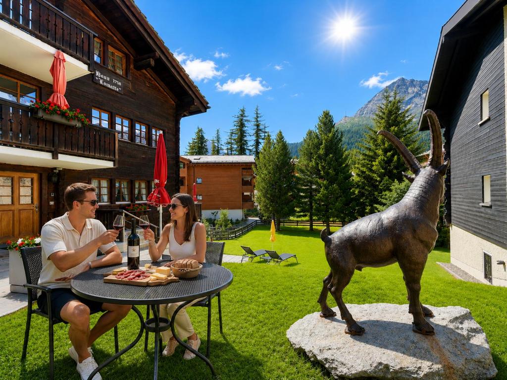 Ein Mann und eine Frau sitzen an einem Tisch neben einer Ziegenstatue. in der Unterkunft Tiny House IBEX in Saas-Fee