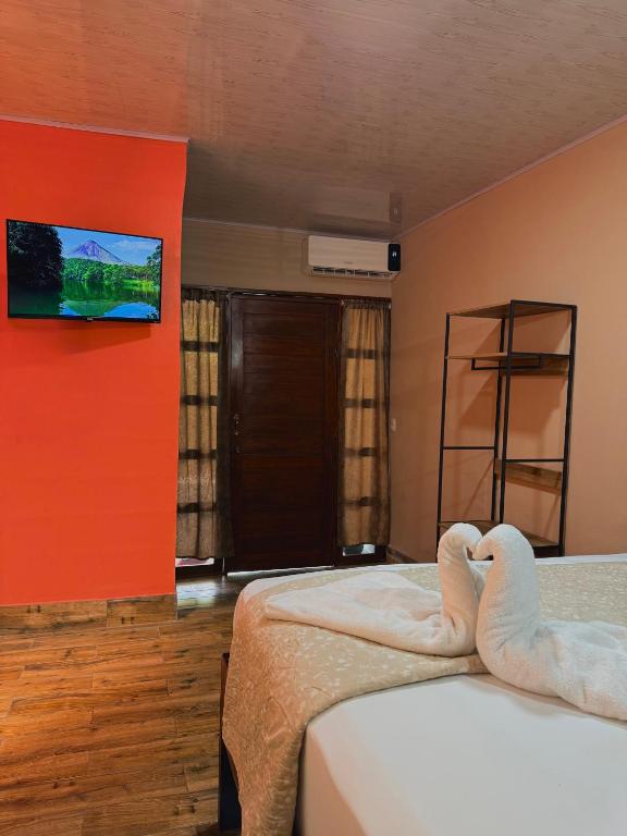 a bedroom with two beds and a tv on the wall at Cabinas Arenal Z-13 in Fortuna