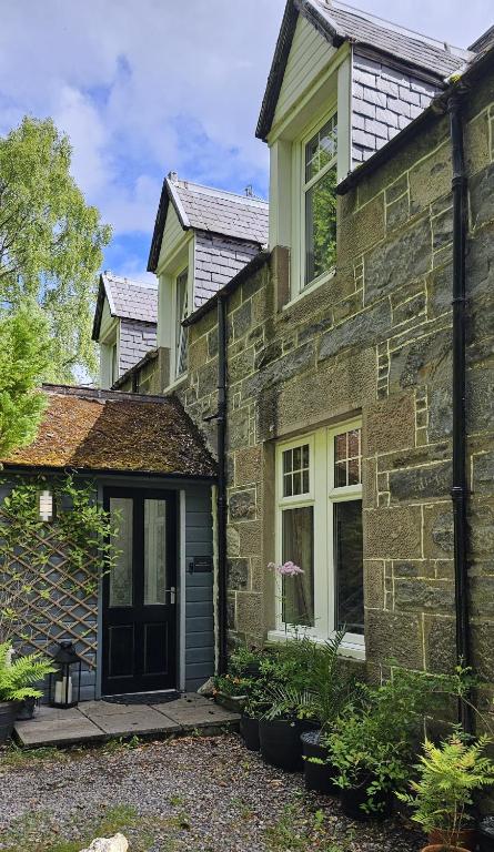 a stone house with a black door and windows at Eagle View Guest House in Newtonmore