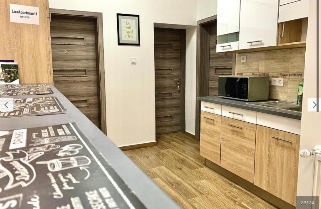 a kitchen with wooden cabinets and a counter top at Downtown Cosy-Rooms in Miskolc