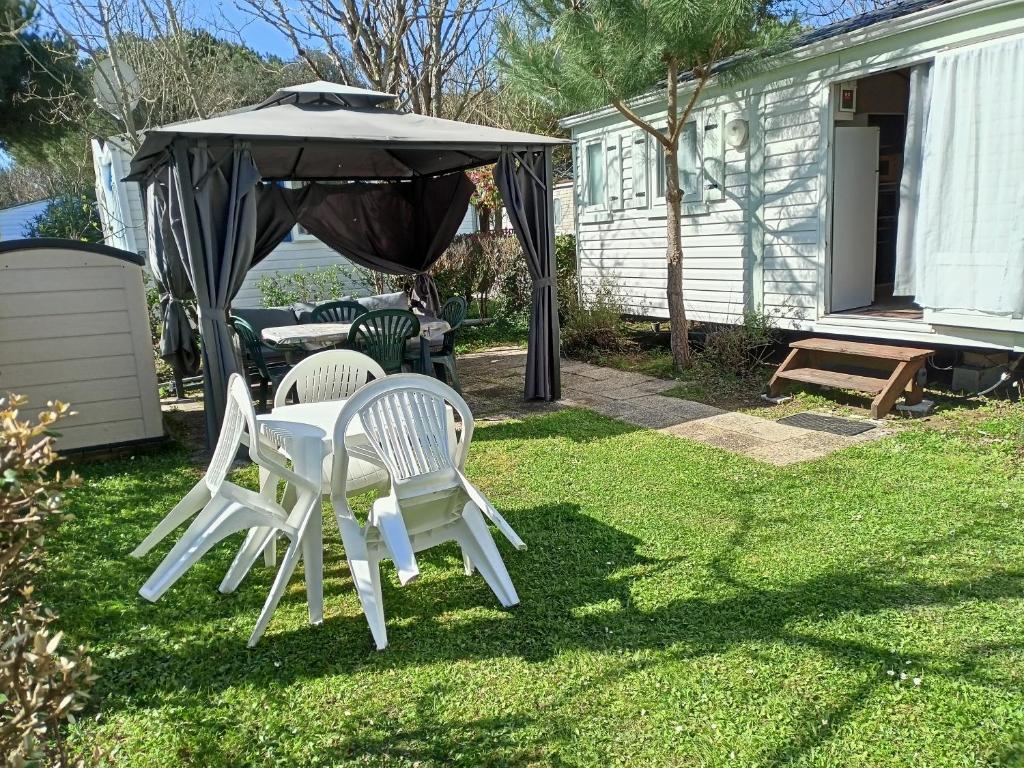 two white chairs and an umbrella in a yard at Thery location 17 in Saint-Pierre-dʼOléron