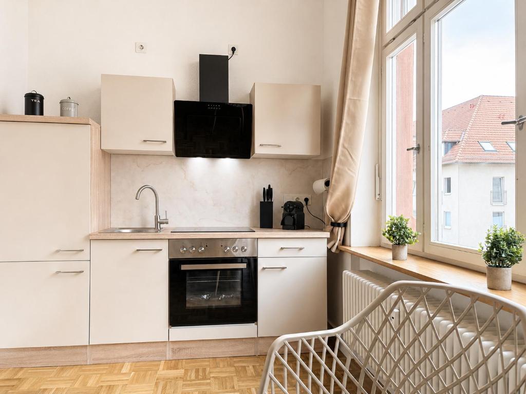 eine Küche mit weißen Schränken, Spüle und Backofen in der Unterkunft Apartment Boho in Cottbus
