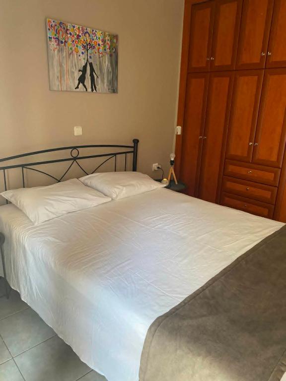 a bedroom with a white bed and a painting on the wall at Calypso Rooms in Preveza