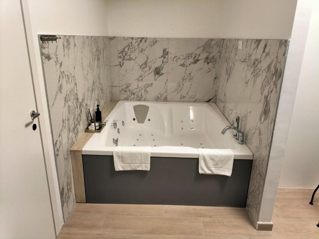 a bathroom with a bath tub with marble walls at B&B Mary House con vasca idromassaggio al centro di Salerno in Salerno