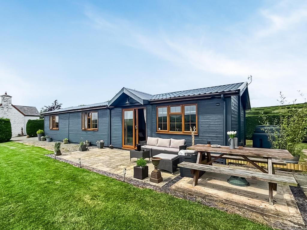 a blue tiny house with a picnic table in the yard at Poundgate Lodge in Knighton