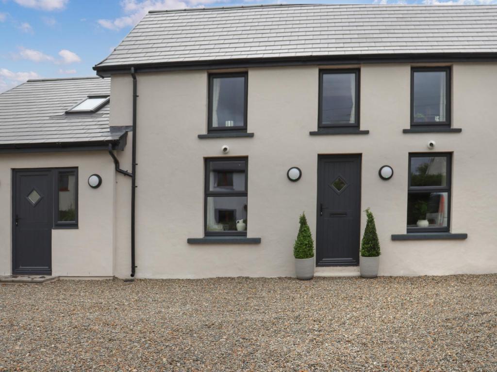 a white house with black doors on a gravel driveway at Brynawel in Maenclochog